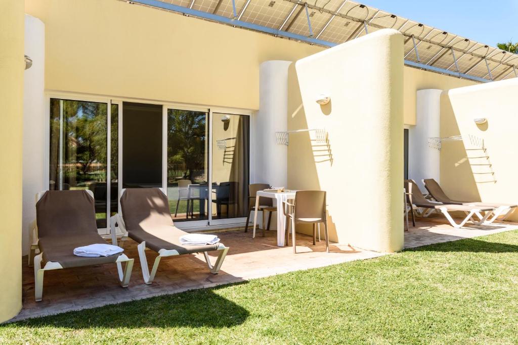 Terrasse privée avec chaises longues et table extérieure devant les chambres.