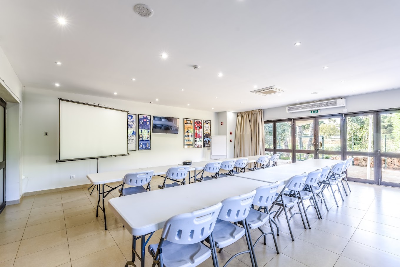 Salle de réunion avec écran de projection et tables configurées pour briefings d'équipe.