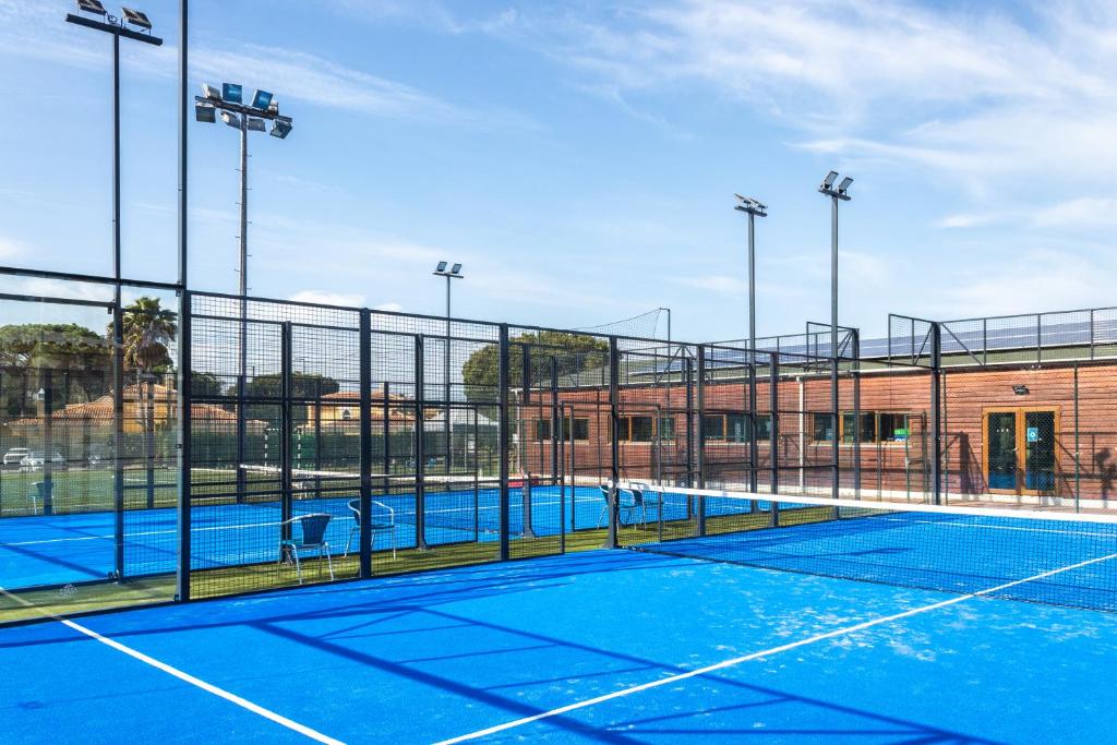 Terrain de padel avec éclairage et chaises à côté de l'aire de jeu clôturée.