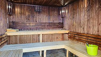 Holzsauna mit Sitzbänken auf zwei Ebenen und Aufgusseimer.