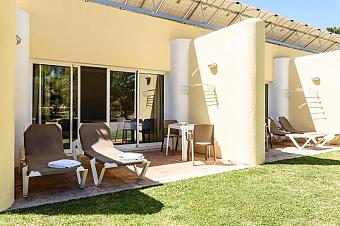 Private Terrasse mit Sonnenliegen und Tisch vor den Gästezimmern.