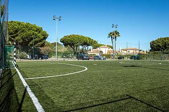 Eingezäunter Kleinfeld-Kunstrasen-Fußballplatz mit Flutlicht.