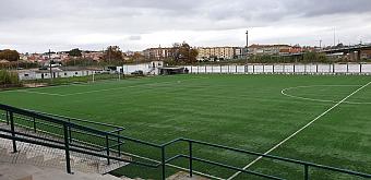 Leerer Kunstrasen-Fußballplatz, von der Tribüne aus an einem bewölkten Tag gesehen.