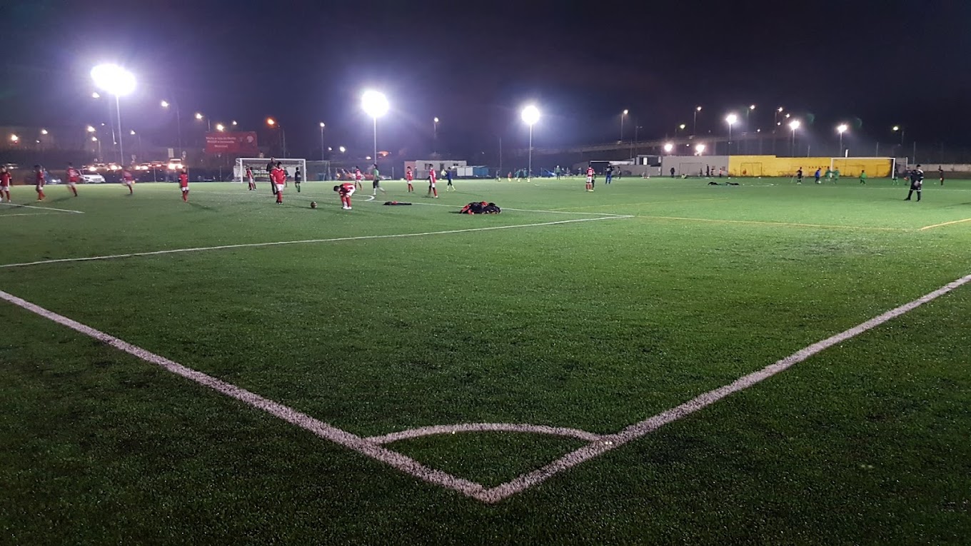 Terrain de football en gazon synthétique éclairé par projecteurs lors d'une séance d'entraînement en soirée.