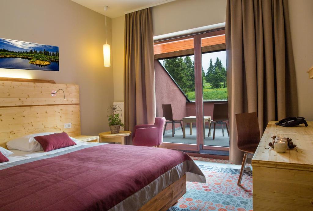 Double room with balcony access, wooden furnishings and red bedding.