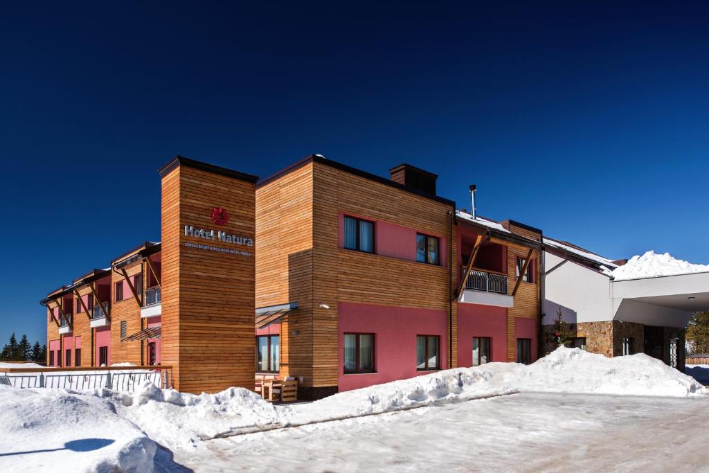Snow-covered hotel exterior with timber cladding under clear winter sky.