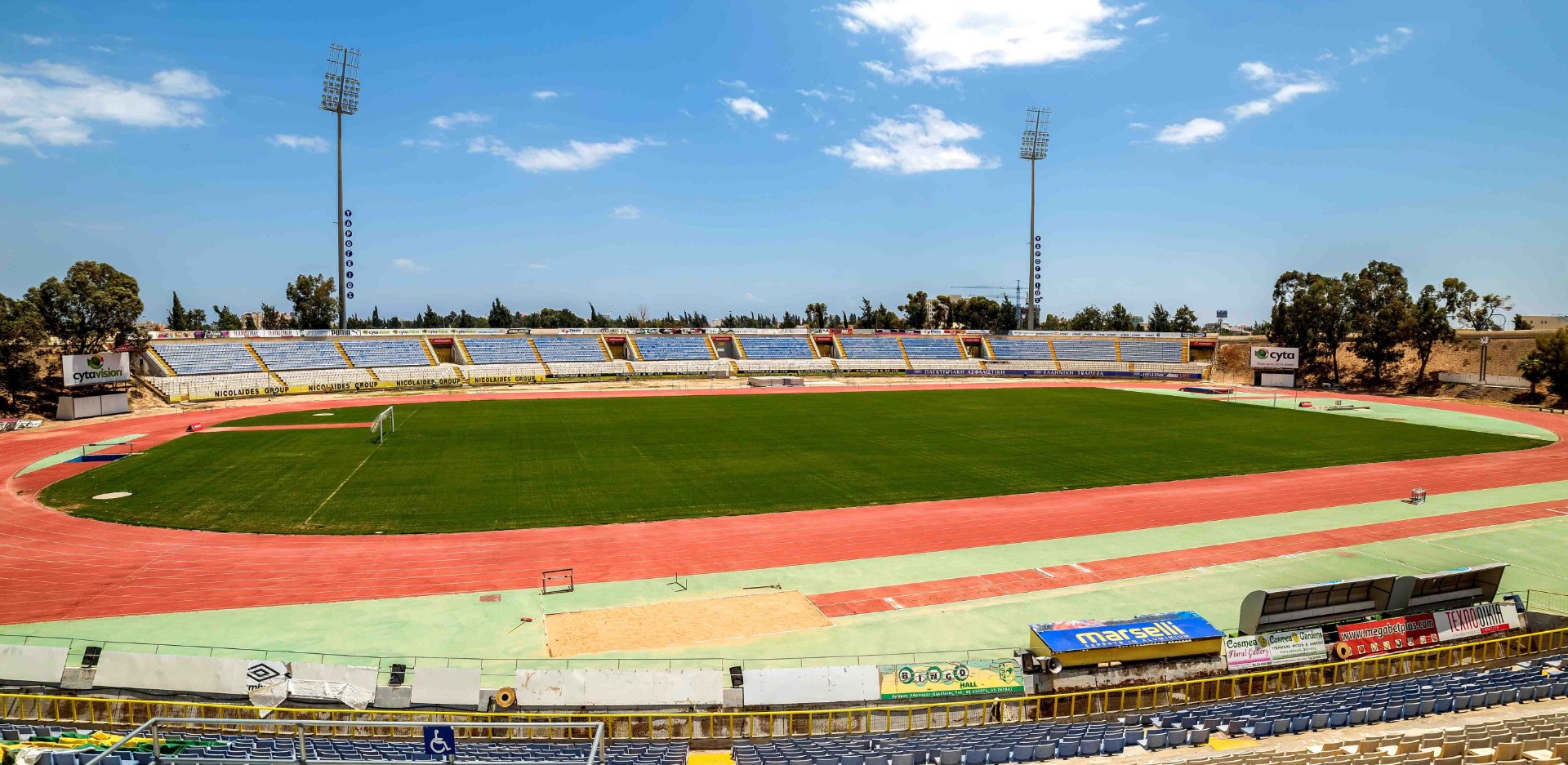 Weitblick auf ein Leichtathletikstadion mit Bahn, Feld und Tribünen.