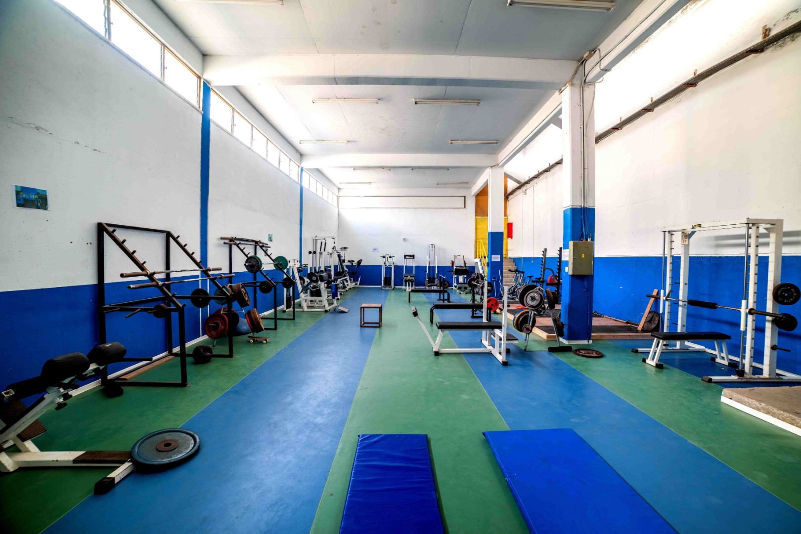 Großer Kraftraum mit Freihanteln, Bänken und Trainingsmatten.