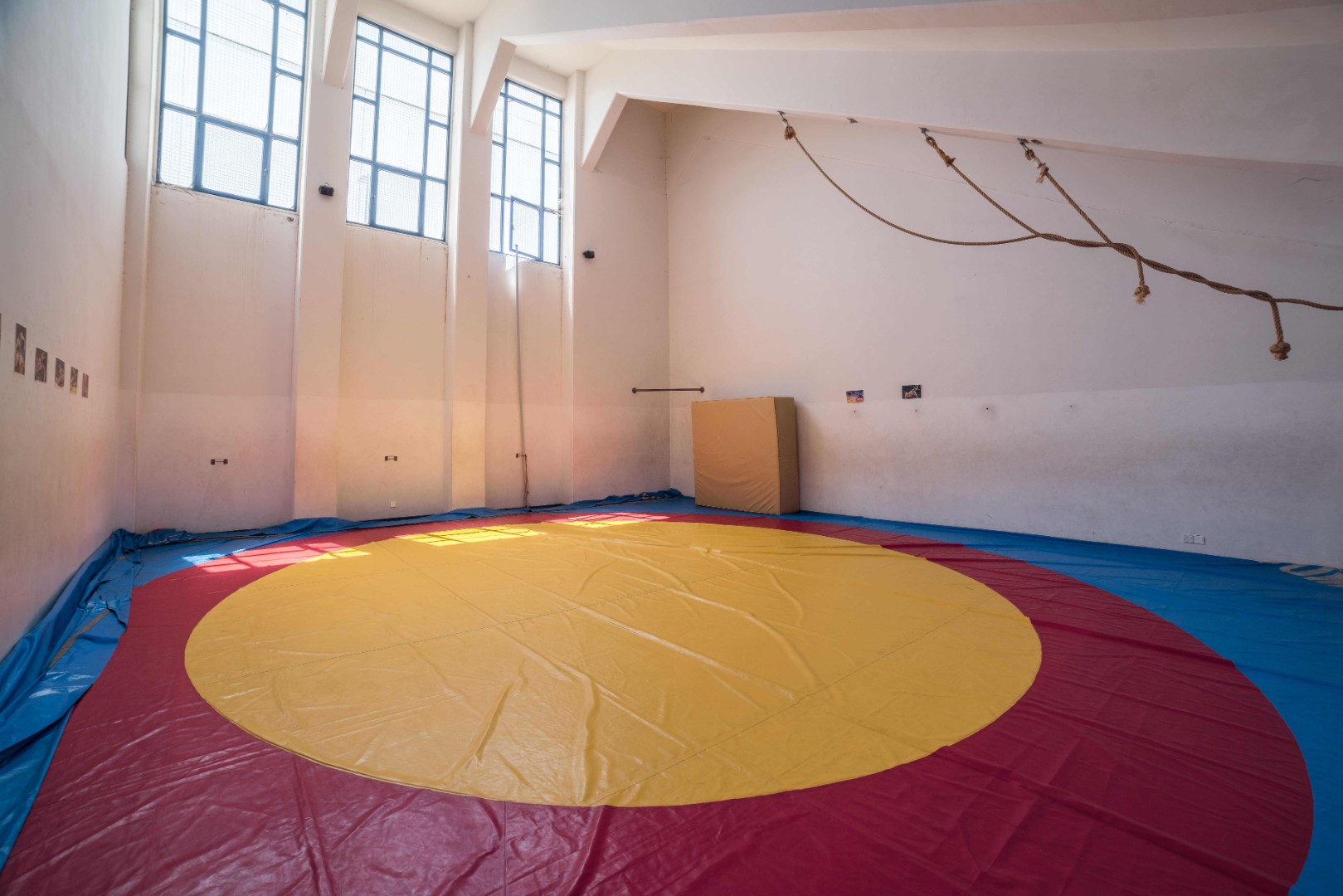 Ringermatte in einer hohen Trainingshalle mit großen Fenstern.
