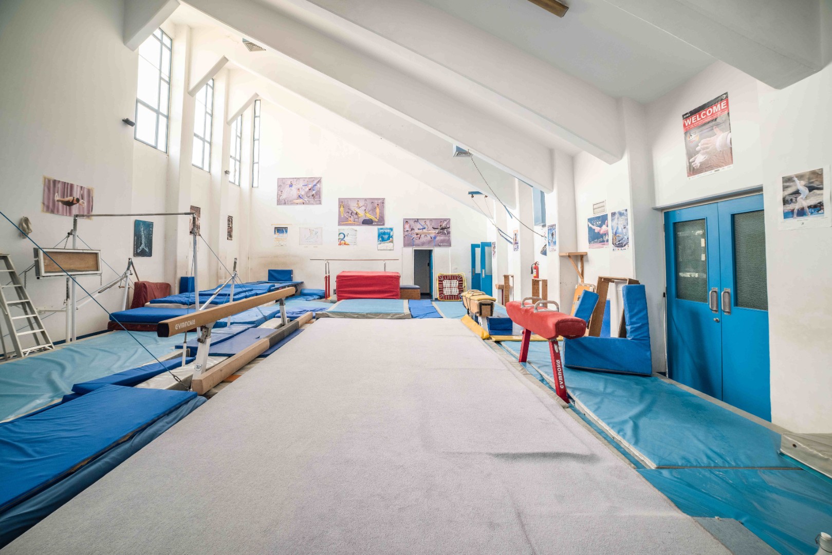 Turnhalle mit Schwebebalken, Pauschenpferd, Landematten und Trainingsfläche.