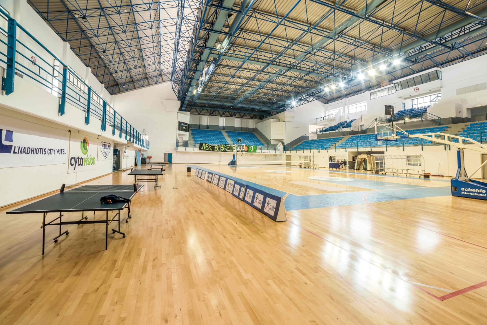 Indoor-Arena mit Basketballfeld, Volleyballnetz und Tischtennisplatten.