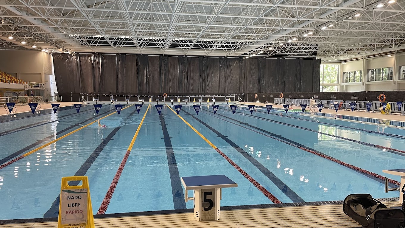 Indoor lap pool with marked lanes, backstroke flags, and starting blocks.