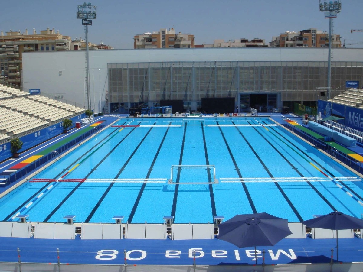 Front view of an outdoor pool and venue facade with grandstand seating.