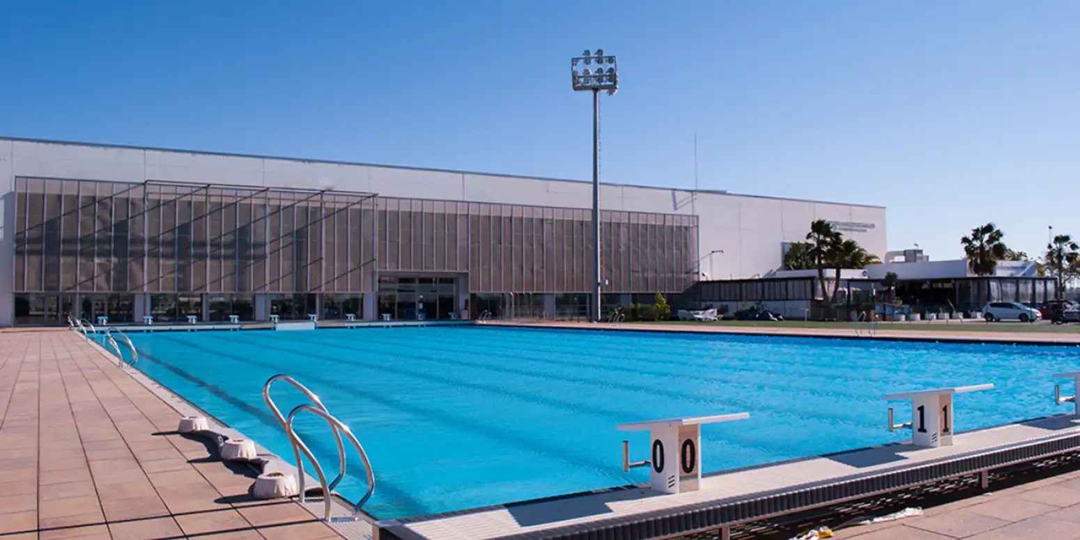 Outdoor pool beside the main venue building under clear daylight.