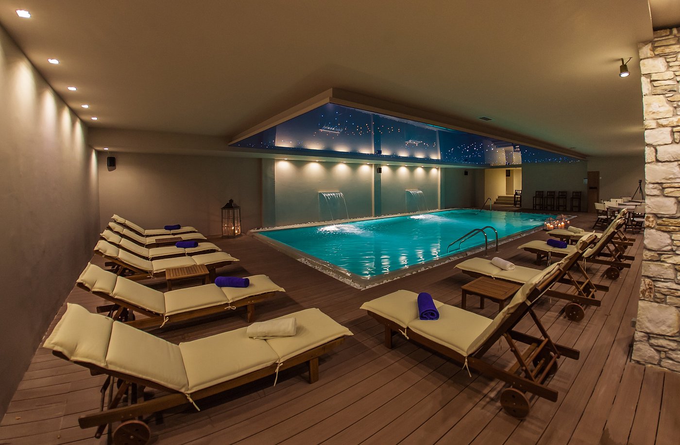 Indoor recovery pool with loungers, water features and low lighting.