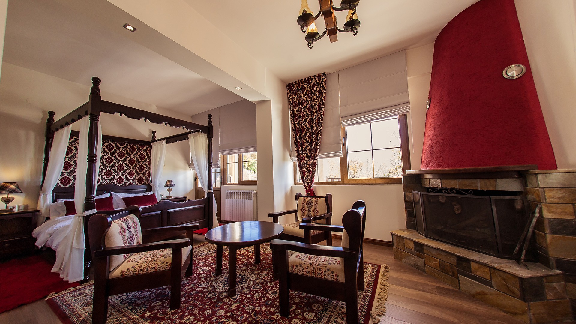 Suite-style room with four-poster bed, fireplace and seating area.
