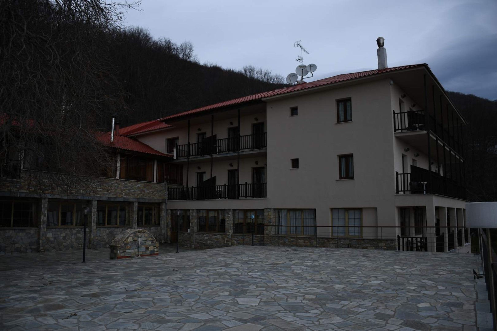 Resort exterior with stone courtyard and forested hillside surroundings.