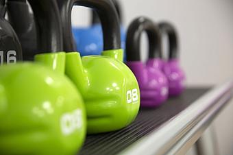 Nahaufnahme bunter Kettlebells, die im Fitnessbereich auf einem Regal aufgereiht sind