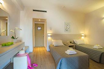 Gemütliches Zweibettzimmer mit sanfter Beleuchtung, heller Einrichtung und ordentlich angeordneten Möbeln