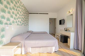 Helles Hotelzimmer mit zwei Einzelbetten, pastellfarbener Tapete und moderner Einrichtung