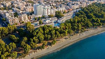 Luftaufnahme eines Strandhotels, umgeben von Bäumen und Stadtgebäuden in Küstennähe