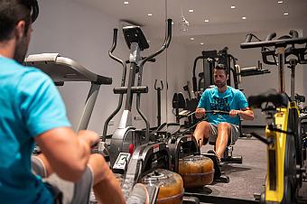 Athlet beim Training auf einer Rudermaschine im Hotel-Fitnessstudio mit mehreren Trainingsgeräten