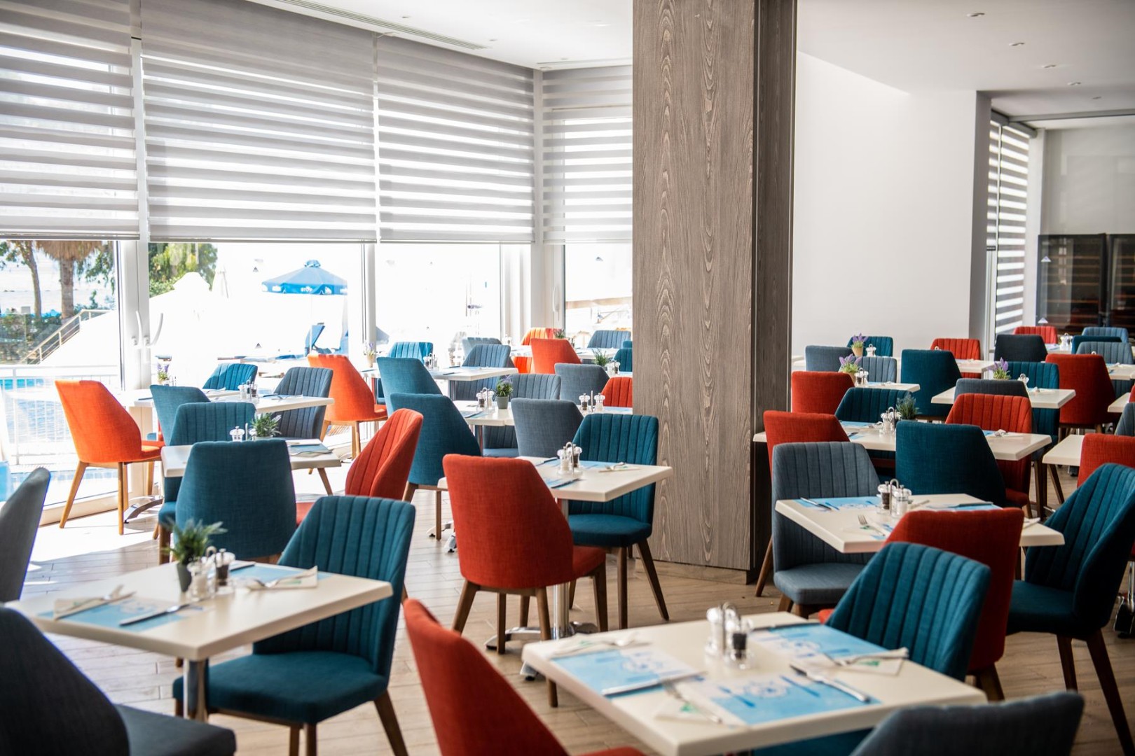 Main restaurant hall with set tables and pool-side windows