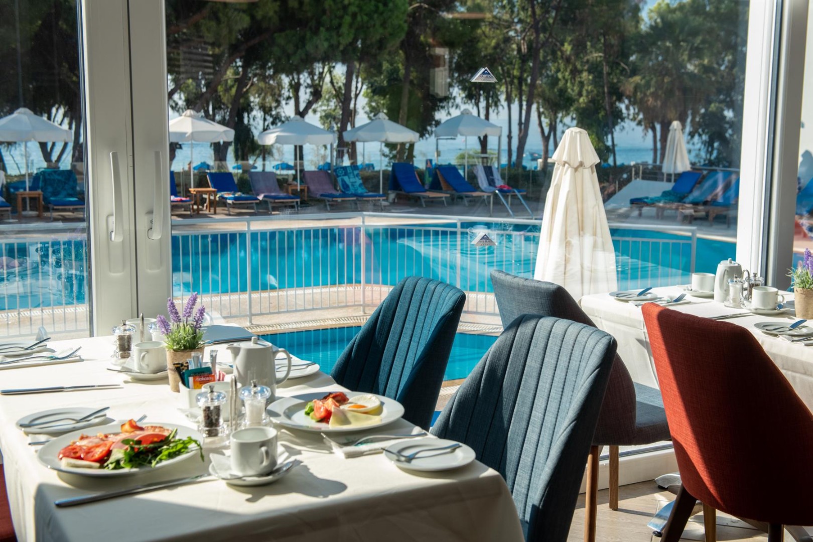 Restaurant dining area with pool-view windows and set tables
