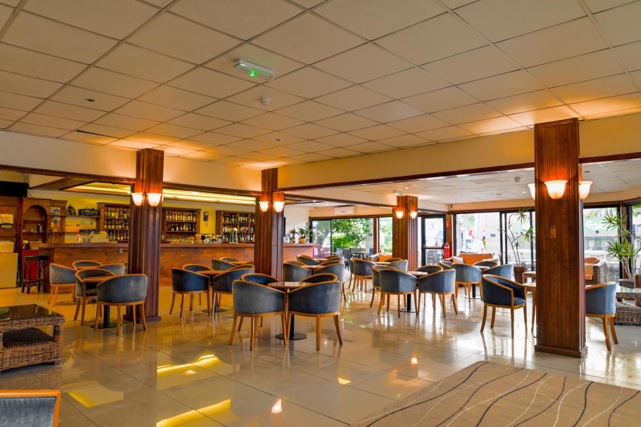Hotel bar lounge with armchairs, wooden columns and large windows.
