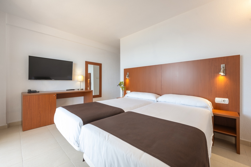 Zweibettzimmer mit zwei Einzelbetten, Schreibtisch, Fernseher und Spiegel.