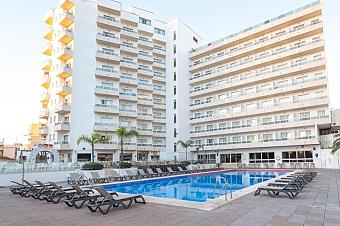 Hotelaußenansicht mit Außenpool und Sonnenliegen im Innenhof.