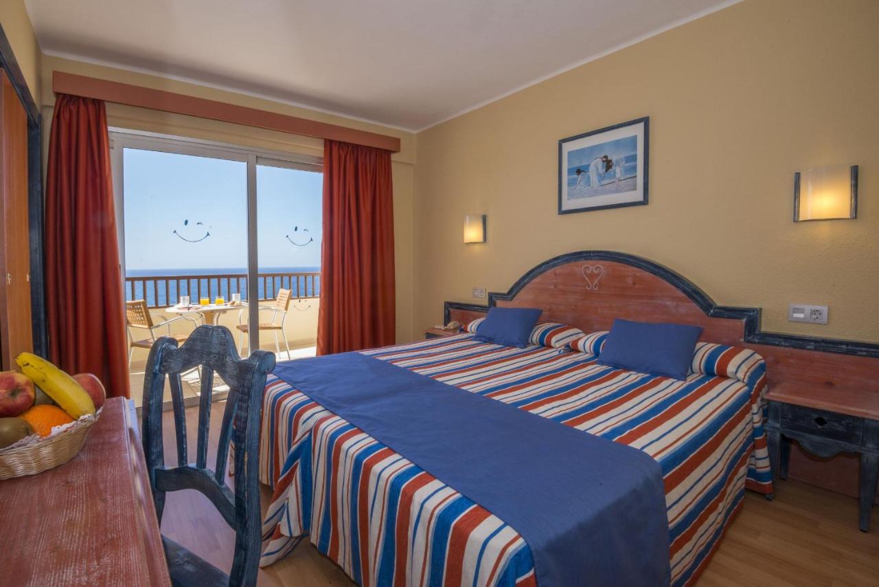 Guest room with double bed and balcony seating facing the ocean.