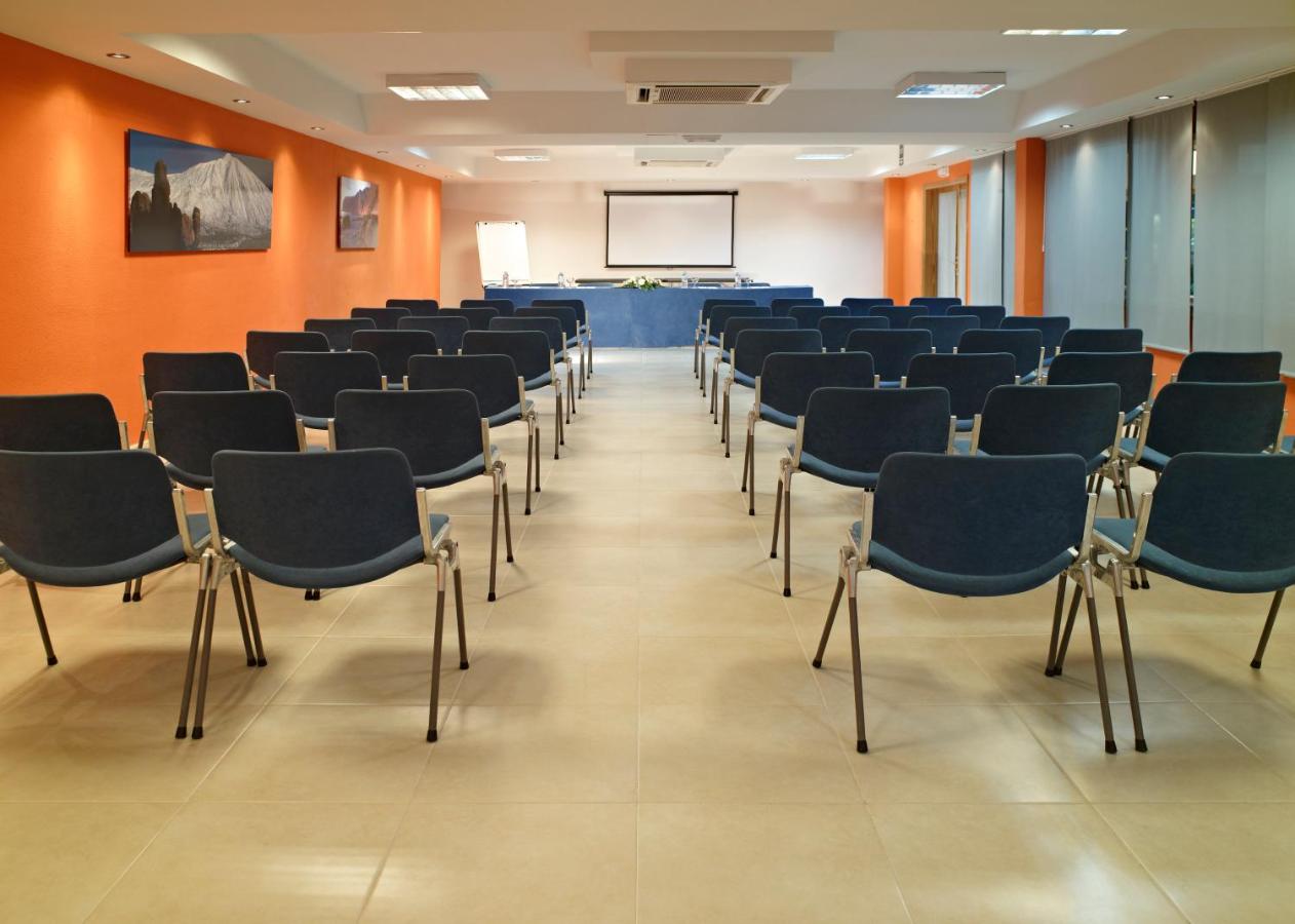 Conference room with projector screen, flip chart, and rows of chairs.