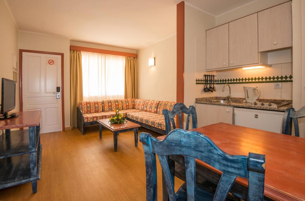 Studio room with dining table, sofa, and kitchenette.