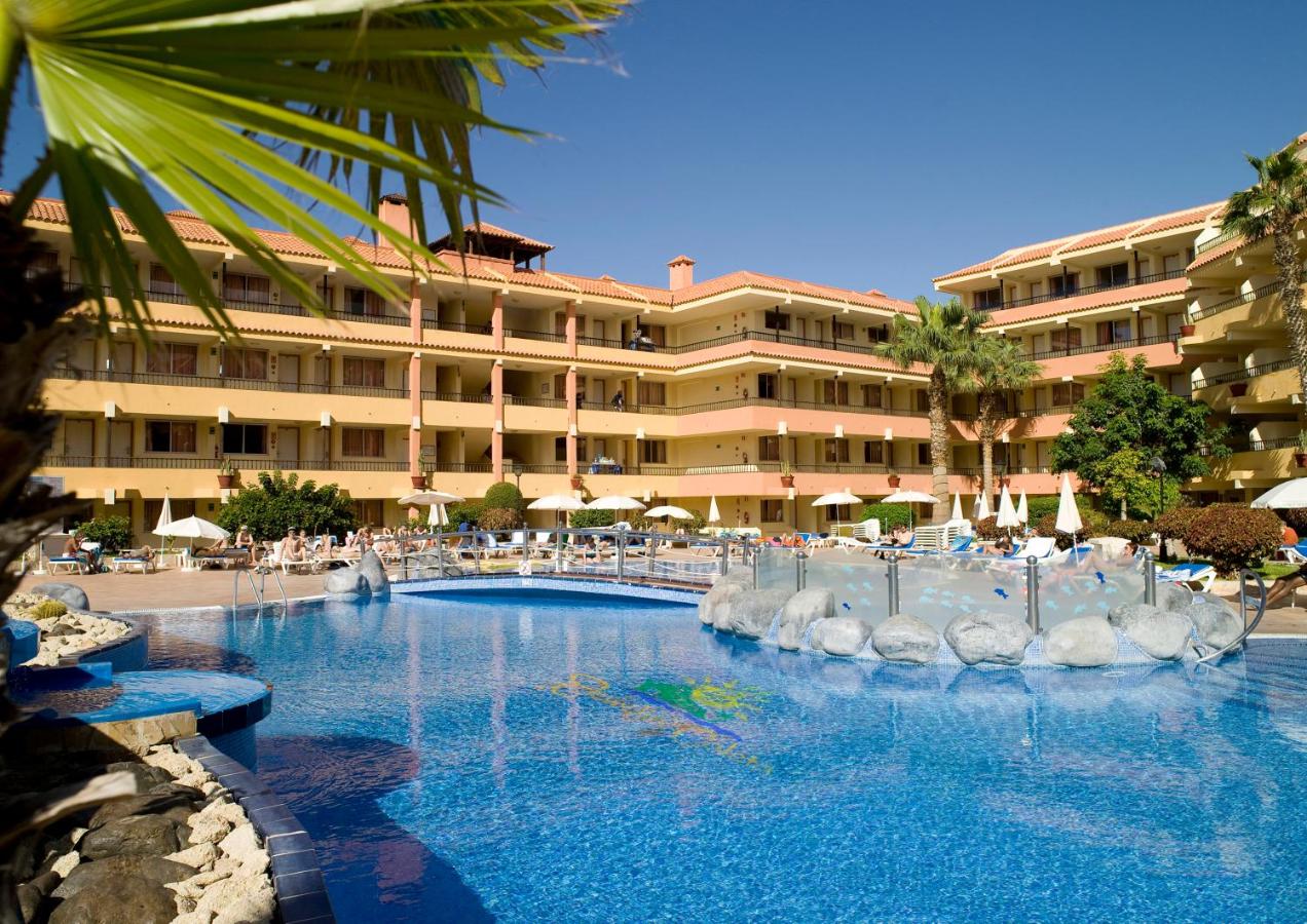 Outdoor pool with rock features, sun loungers, and surrounding hotel balconies.