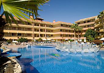 Outdoor pool with rock features, sun loungers, and surrounding hotel balconies.