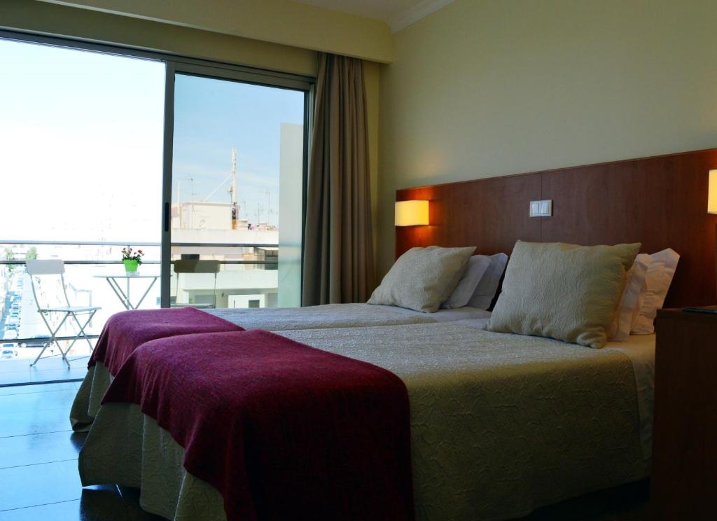 Chambre twin avec accès au balcon et petite table d'extérieur avec chaises.