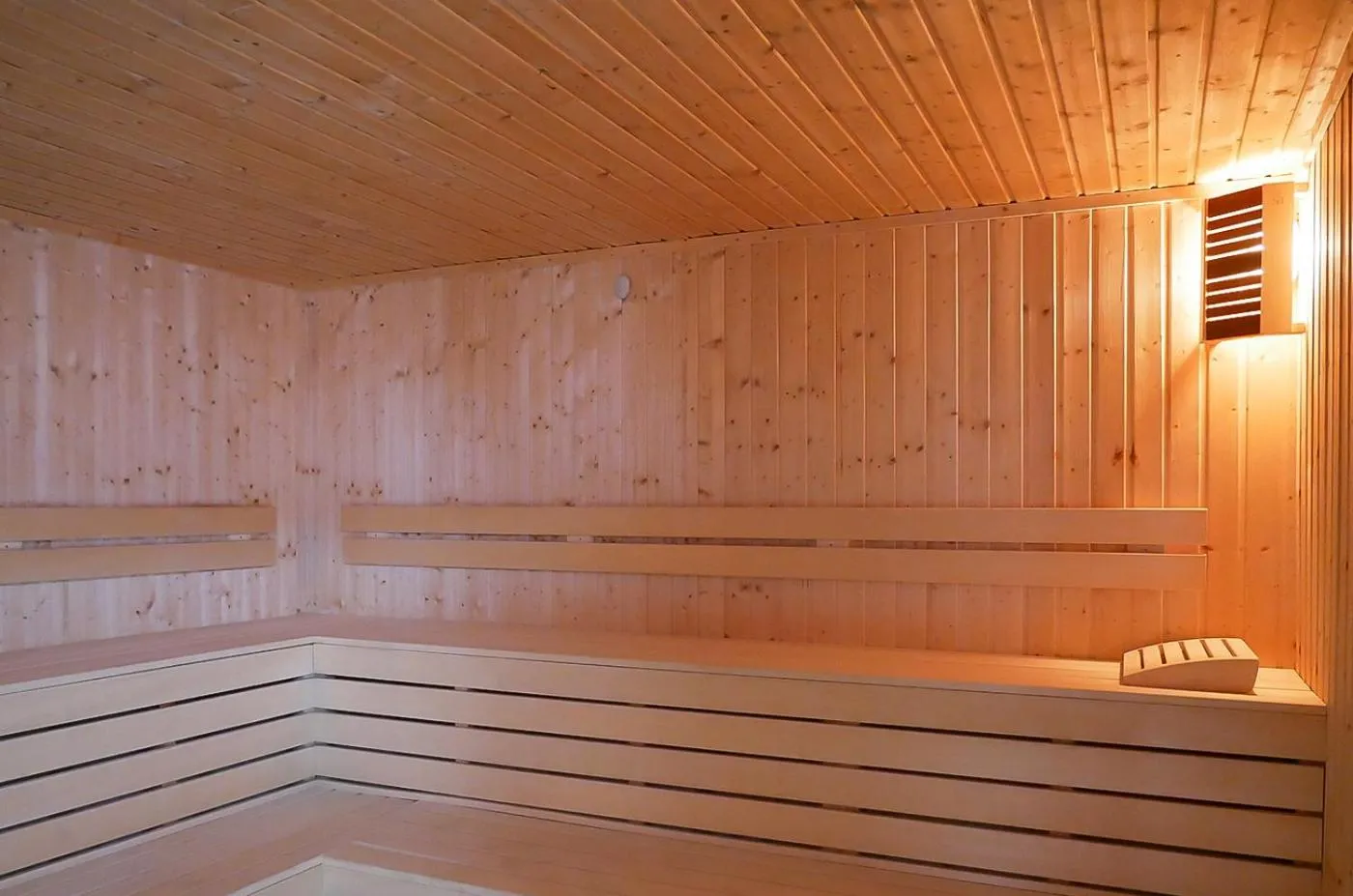 Holzsauna mit gestuften Sitzbänken und warmer Beleuchtung, Regenerationseinrichtung für Athleten nach den Trainingseinheiten
