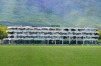 Hotelgebäude mit Blick auf einen grünen Fußballplatz und Berge im Hintergrund, Unterkunft für ein Sporttrainingslager