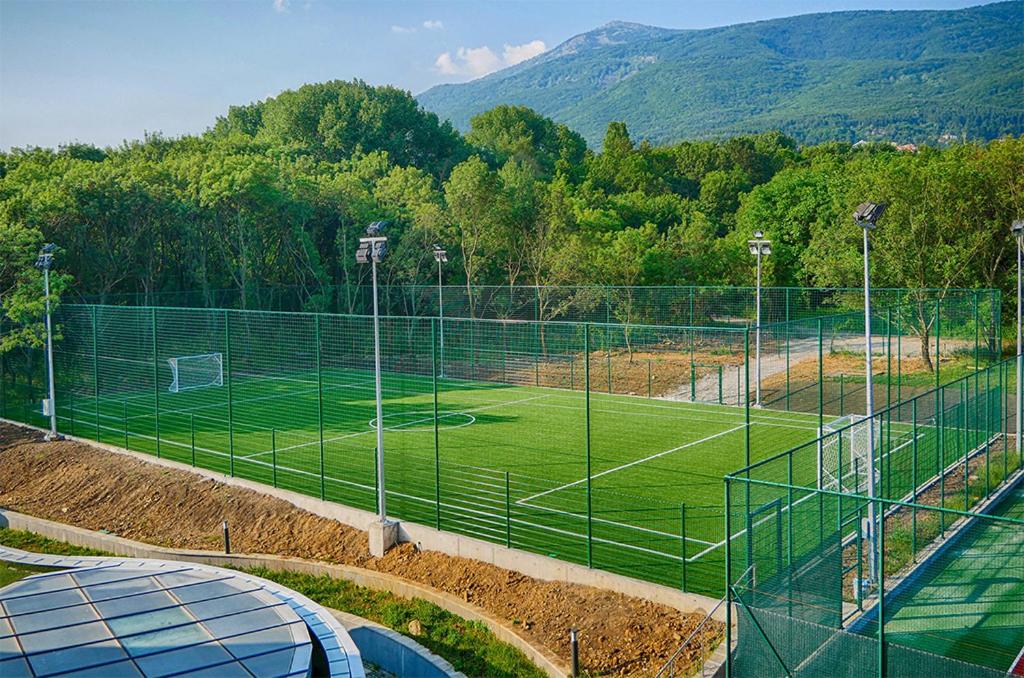 Eingezäunter Kunstrasen-Fußballplatz mit Toren und Flutlicht, genutzt für Trainingslager-Übungen