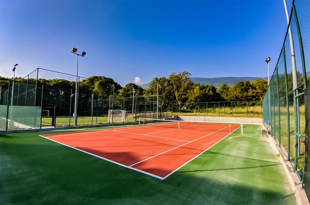 Außen-Tennisplatz mit roter und grüner Oberfläche, eingezäunt und beleuchtet für Trainingseinheiten im Trainingslager