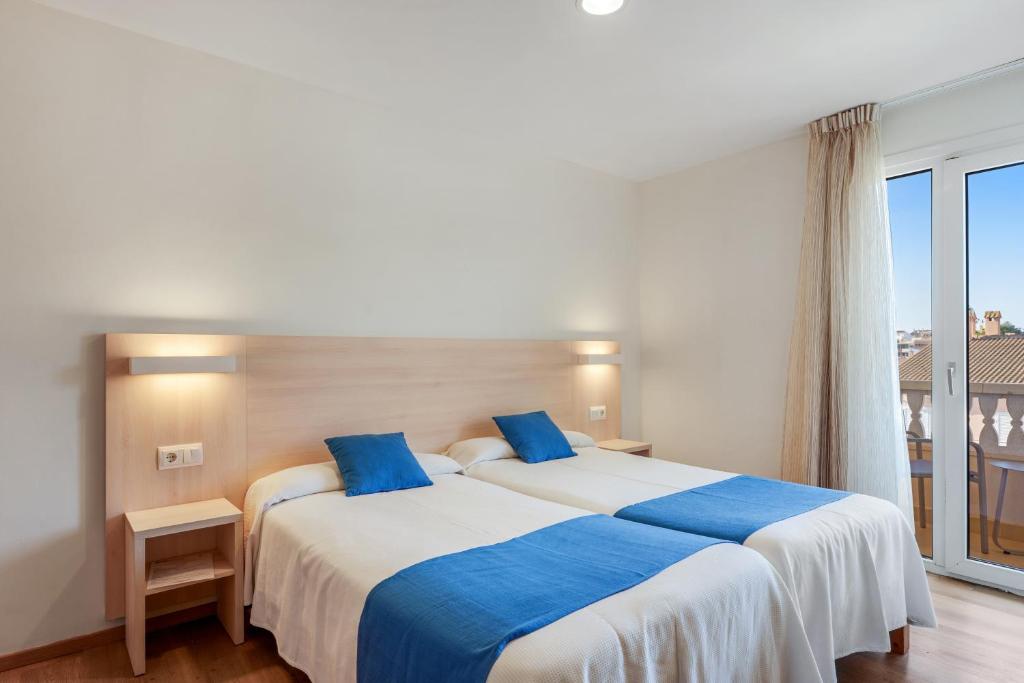 Chambre twin avec portes-fenêtres donnant sur balcon, deux lits et salle de douche visible.