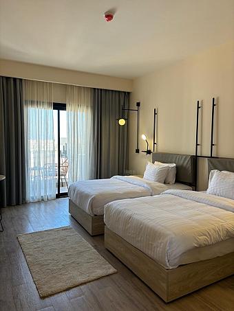 Guest room with two single beds, rug, and balcony access