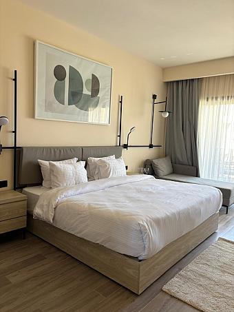 Guest room with double bed, wall art, and large window with curtain