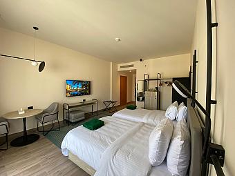 Spacious room with two single beds, seating area, and wall-mounted TV