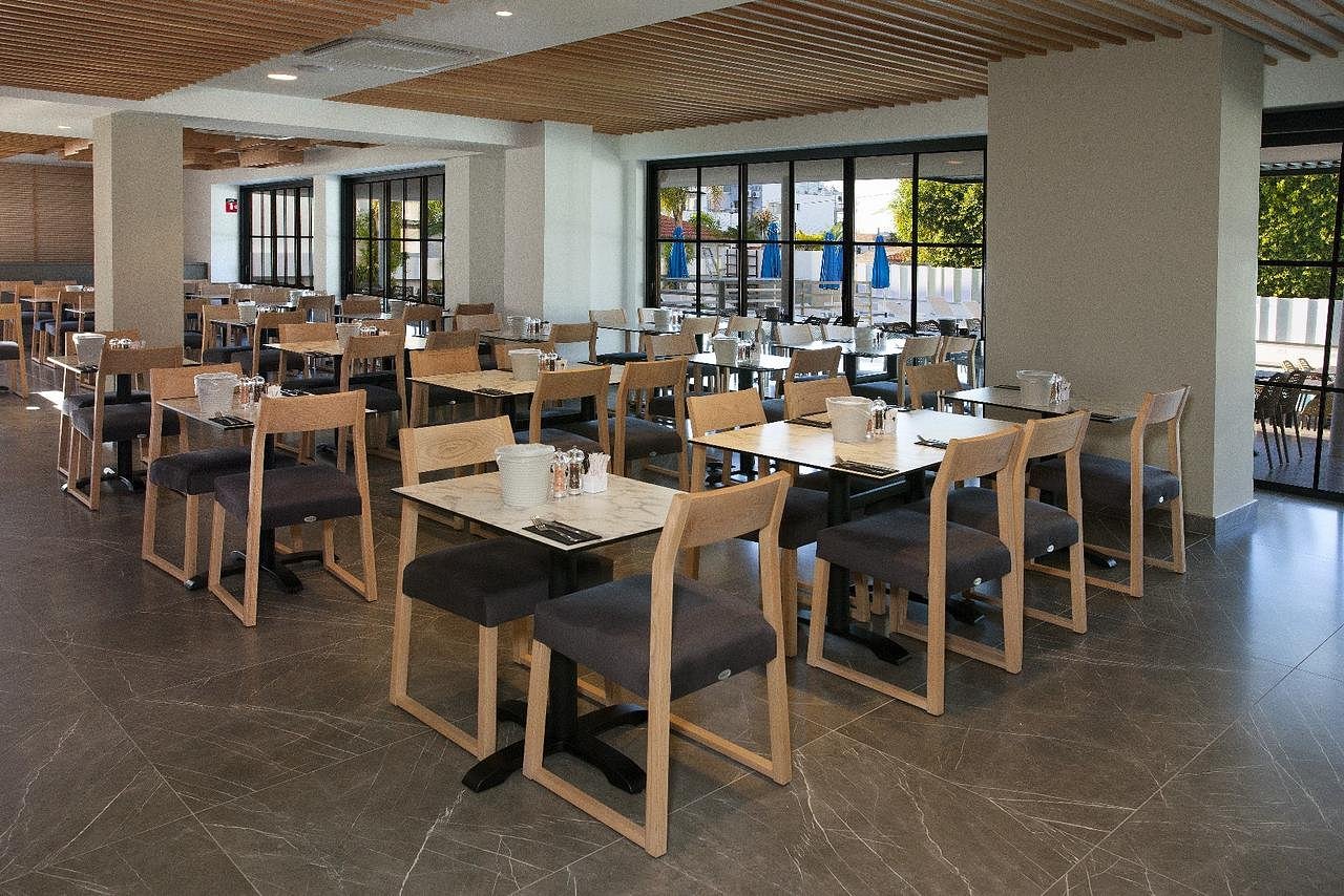 Bright restaurant dining area with neatly arranged tables, chairs and large windows.
