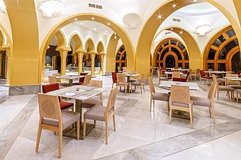 Restaurant with arched golden walls, marble floors, and neatly set tables