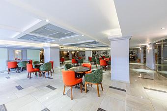 Indoor lounge with red and green chairs around tables on polished floor