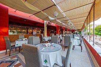 Outdoor dining terrace with round tables, white tablecloths, and canopy roof