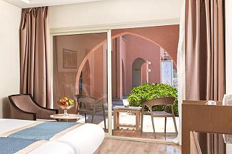 Guest room with double bed, fruit bowl, and terrace with outdoor chairs